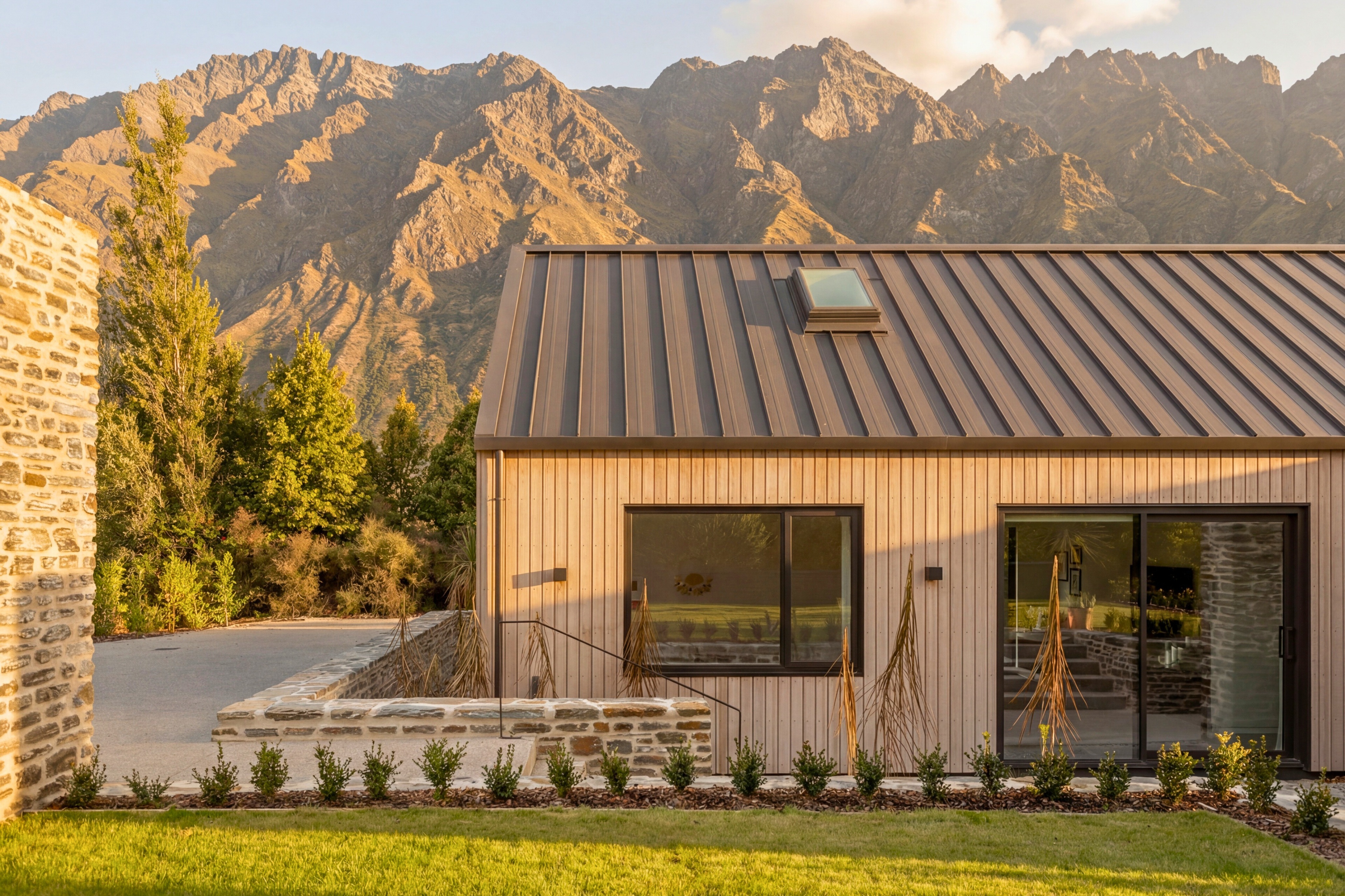 Exterior view of the cedar and schist dwelling with mountain backdrop and native planting